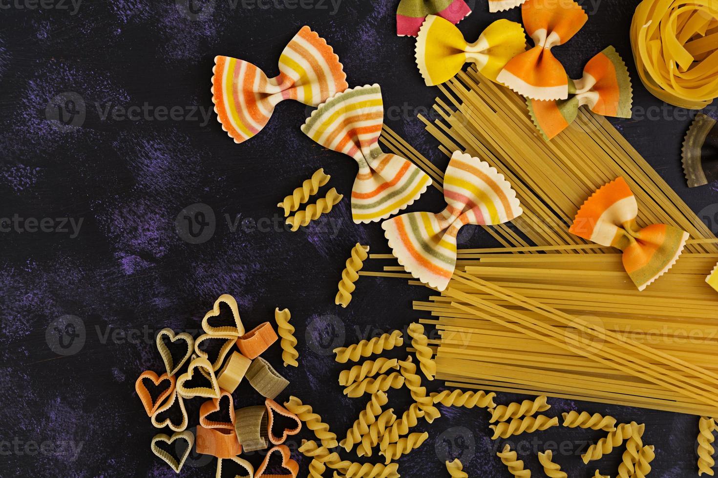 Dry pasta background. Different pasta on dark background. Flat lay. Top view. photo