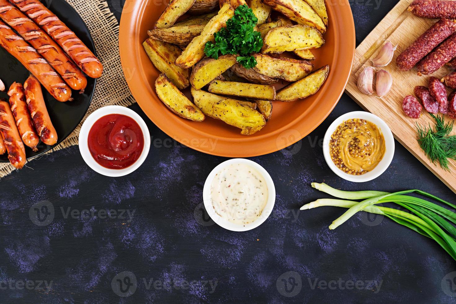 Baked potato wedges with sausages and spices. Top view photo