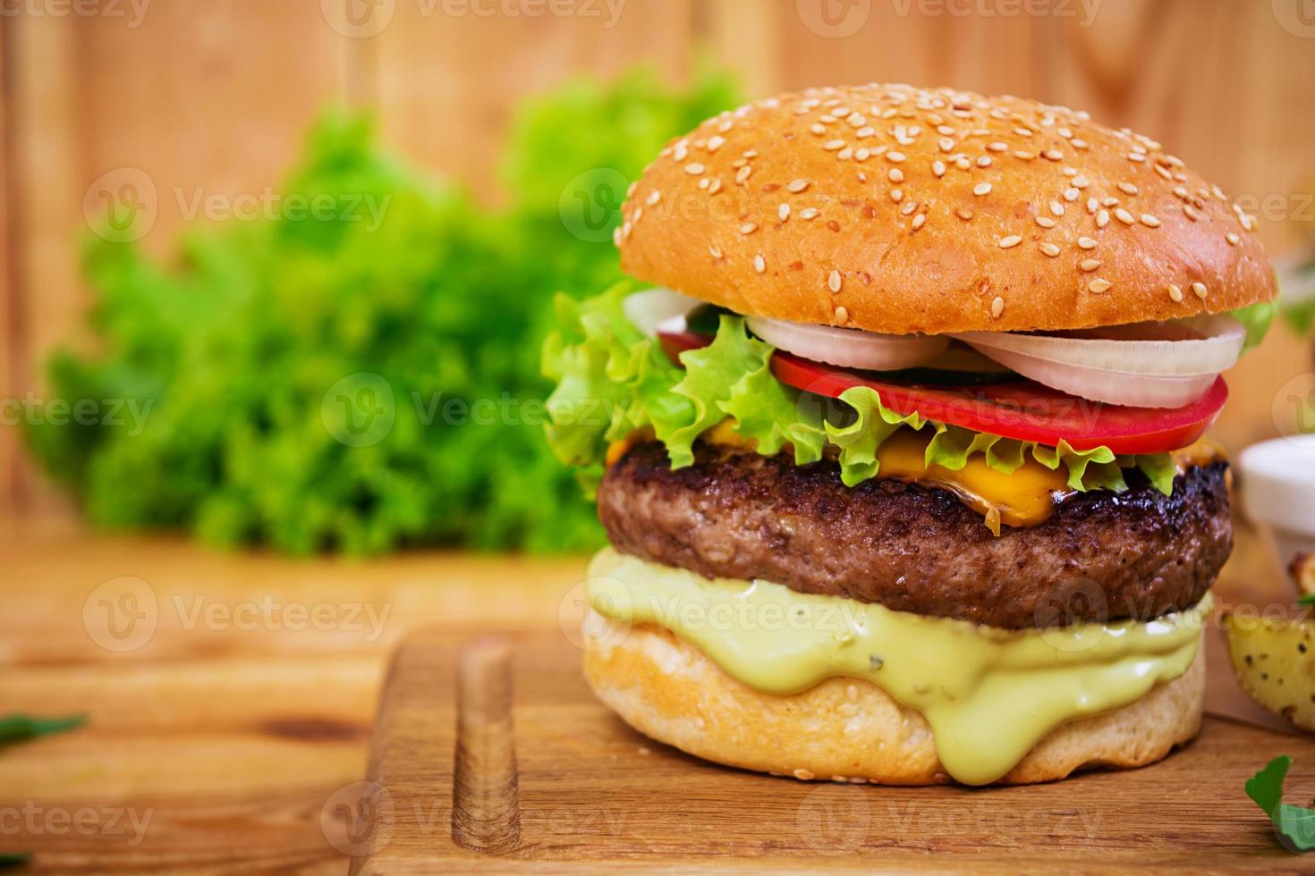 Delicious handmade burger on wooden background. Close view photo