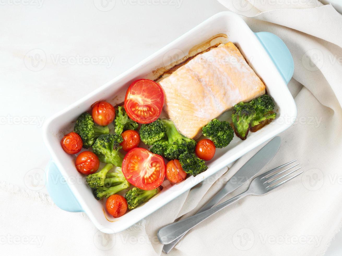 pescado salmón al horno con verduras - brócoli, tomates. alimentos dietéticos saludables, fondo de mármol blanco, vista superior. foto