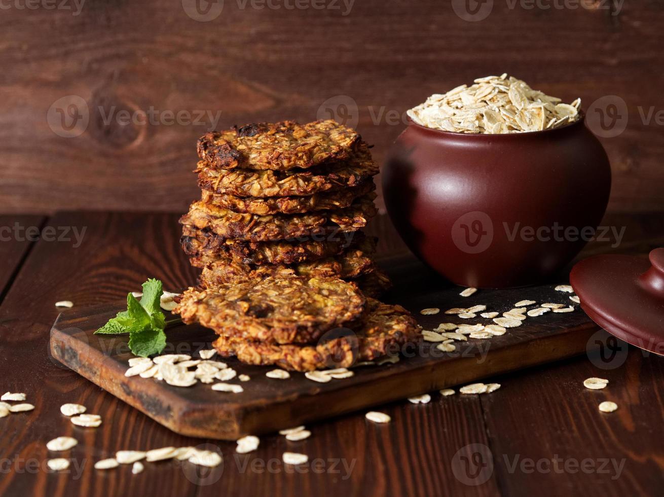 Homemade oatmeal cookies with banana, oats, nuts, eggs and flour free on brown dark wooden table, side view. photo