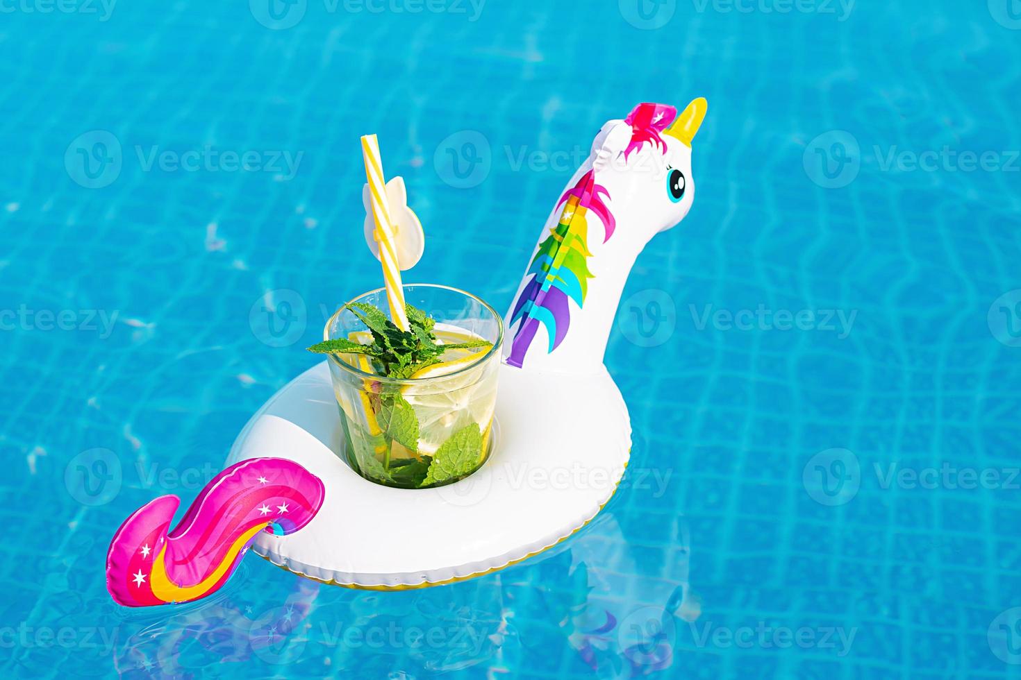 Fresh coctail mojito on inflatable white unicorn toy at swimming pool. Vacation concept. photo