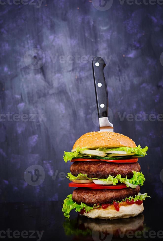 deliciosa hamburguesa hecha a mano sobre fondo oscuro. vista cercana foto