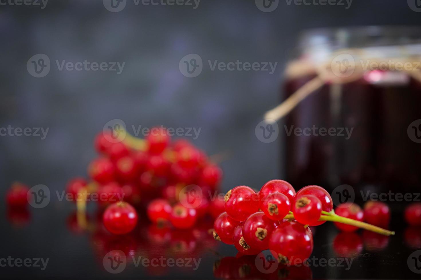Jar with jam of red currant on dark background photo