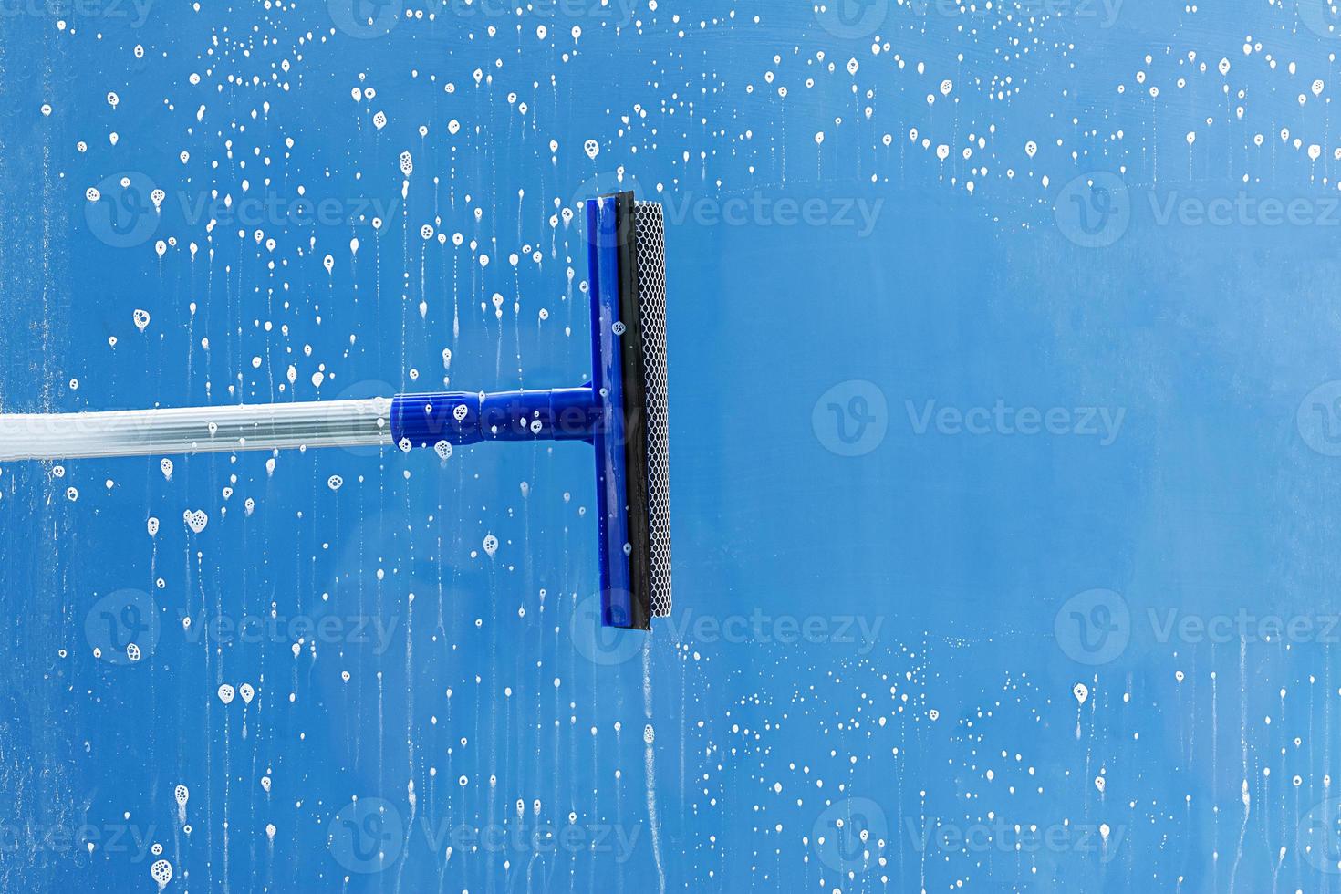 Rubber squeegee cleans window. Clears a stripe of soaped window. Cleaning service concept. photo