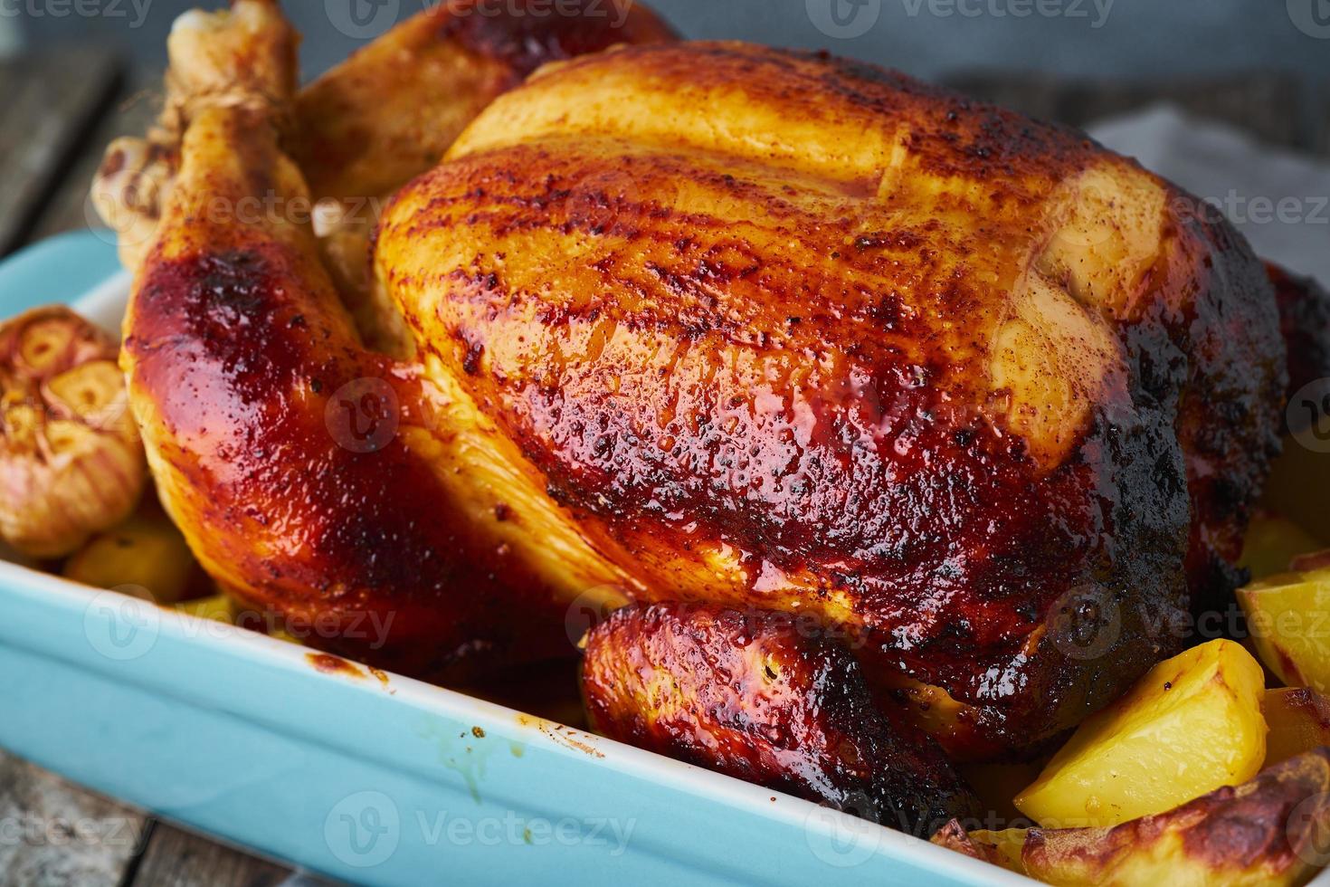 Baked whole chicken in blue casserole on dark gray old wooden table photo