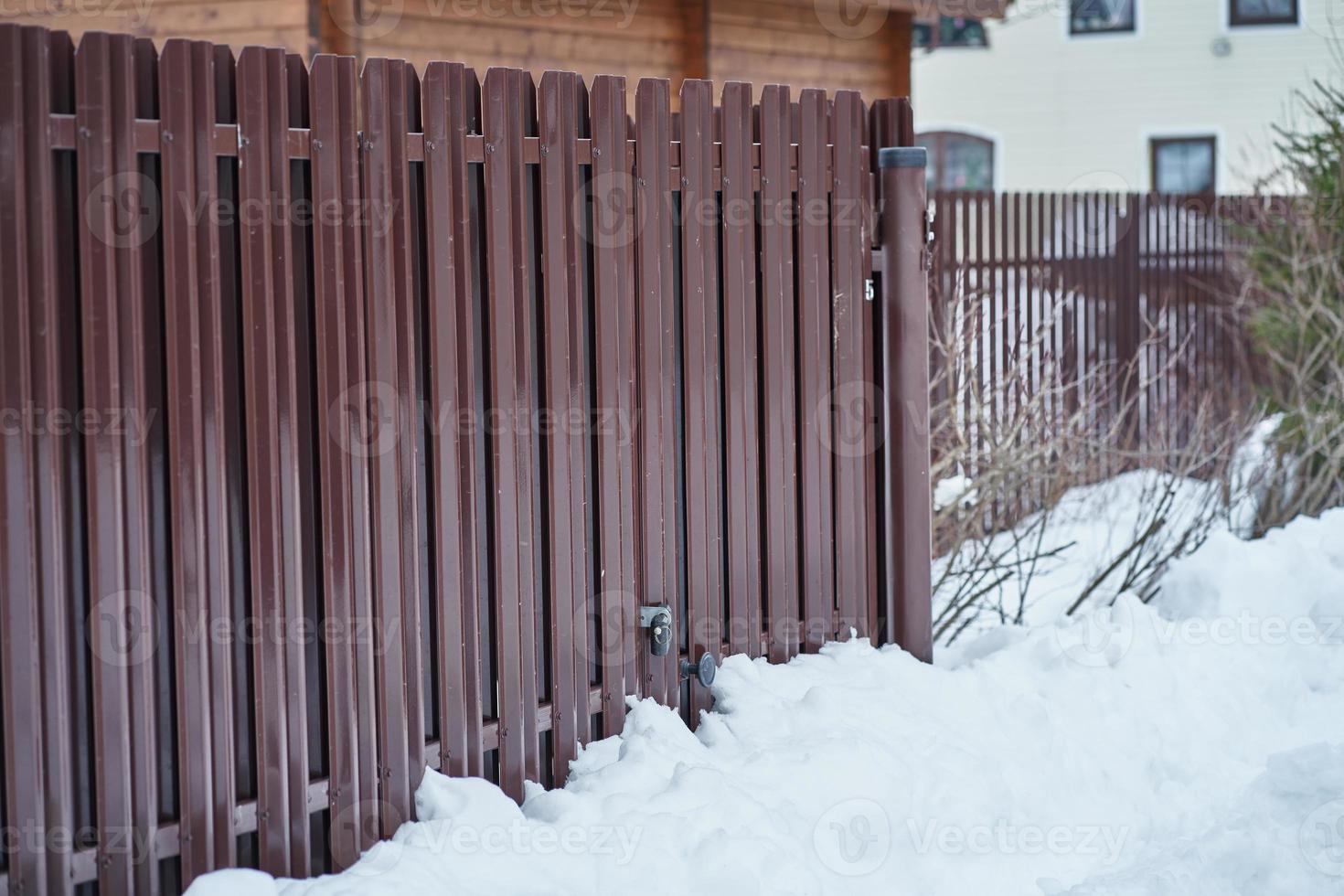 Metal Fence and snow in countryside, gate with padlock, side view photo