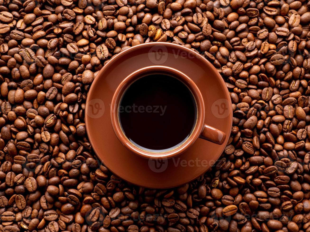 brown cup of espresso on background of scattered coffee beans, top view, close up, macro photo