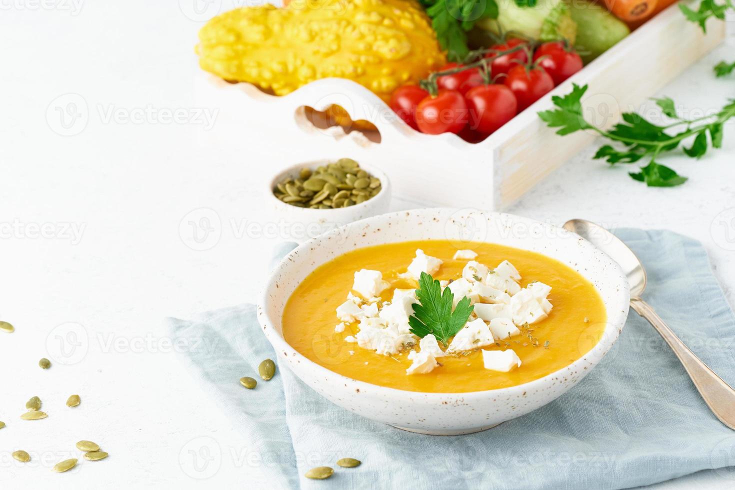 Pumpkin cream soup with feta cheese, autumn homemade food, white background, closeup, copy space photo