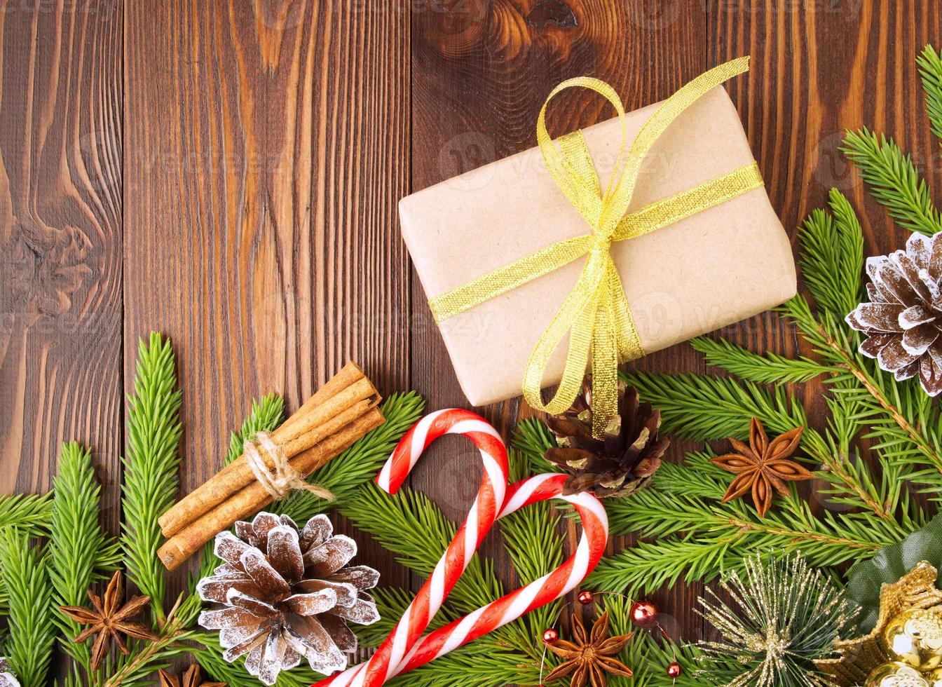 fondo de navidad y feliz año nuevo. caja de regalo de navidad de papel kraft, ramas de abeto, conos, canela, mesa de madera. foto