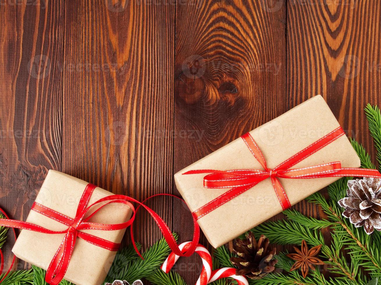 navidad y feliz año nuevo fondo marrón oscuro. caja de regalo de navidad, ramas de abeto, mesa de madera, vista superior, espacio de copia foto