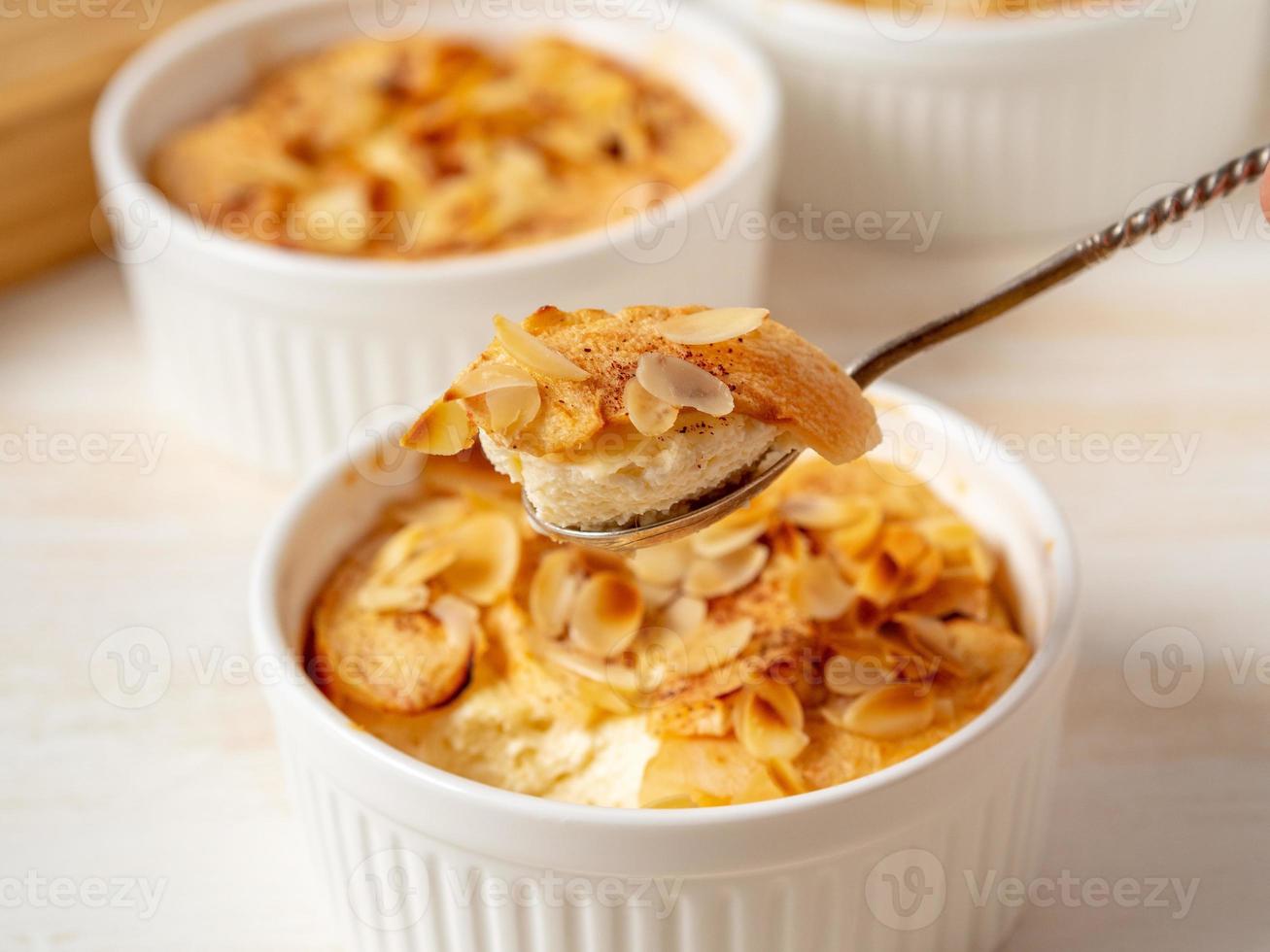 Cheesecake on white wooden table in kitchen. Delicate curd dessert with apples, almond flakes photo
