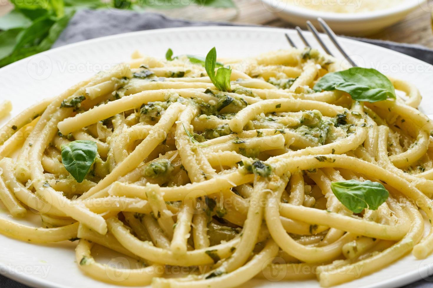 Pesto spaghetti pasta with basil, garlic, pine nuts, olive oil. Rustic table, macro photo