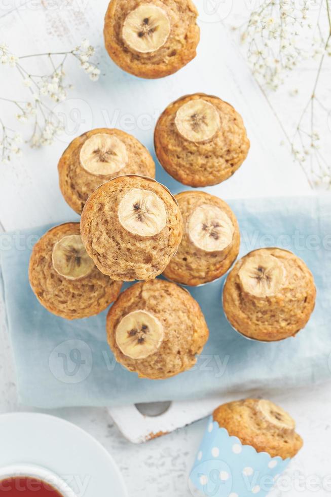 Banana muffin, top view, close up, vertical. Morning breakfast on blue napkin, white concrete table photo