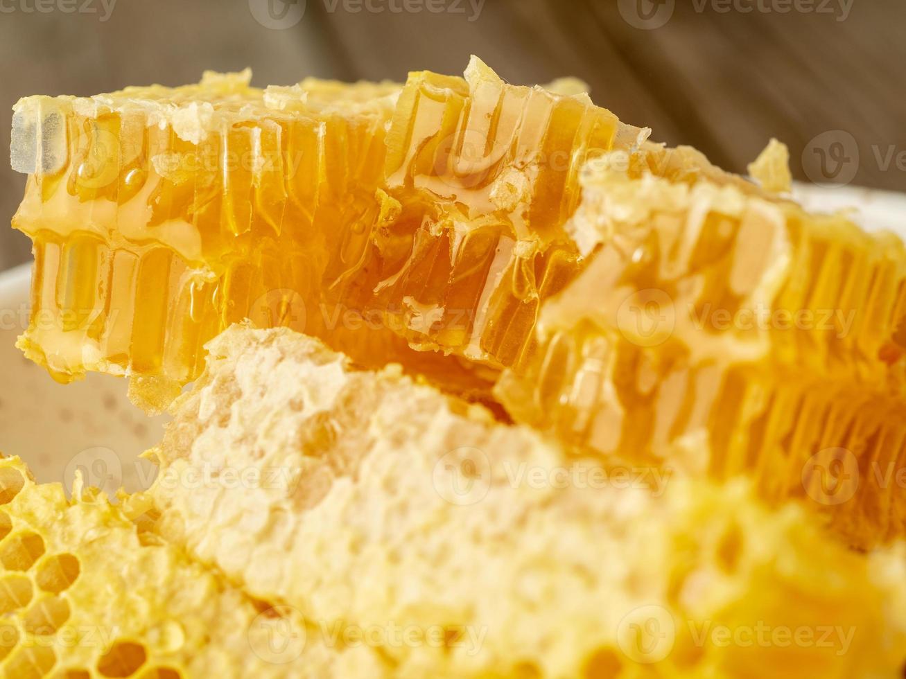 honey in honeycomb, close-up, on white ceramic plate, on wooden rustic table, photo