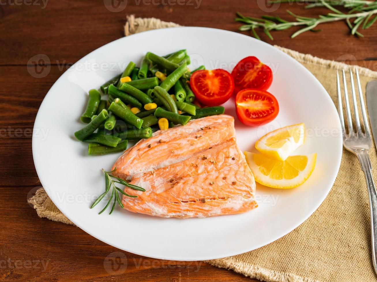 Fish salmon steamed with vegetables. Healthy diet food, dark wooden backdrop photo