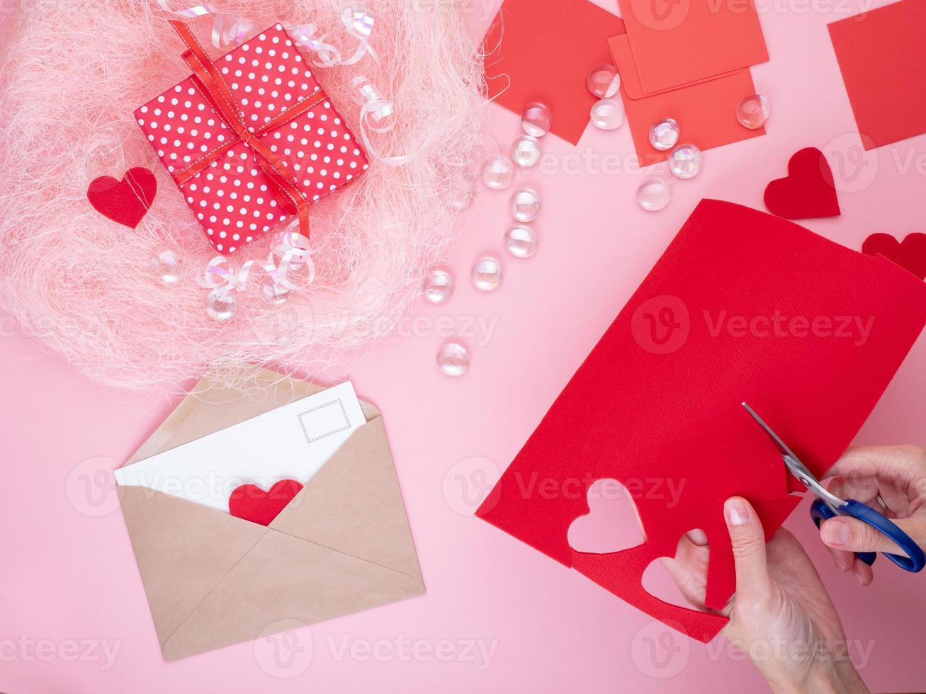 woman cuts out red felt hearts, homemade crafts for Valentine's day, hand made creativity, top view photo