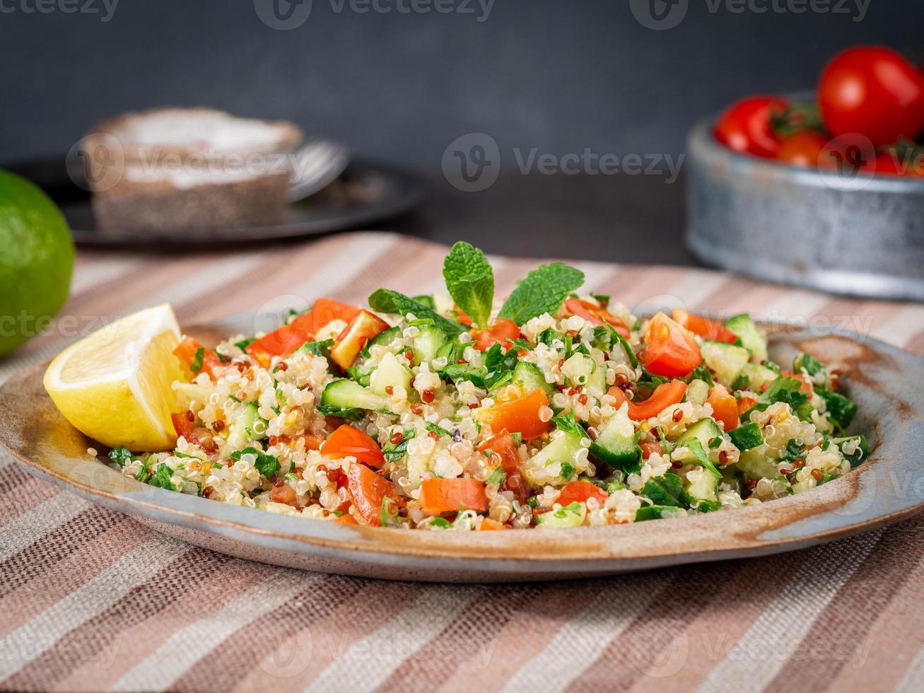 Tabbouleh salad with quinoa. Eastern food with vegetables mix, vegan diet. Side view photo