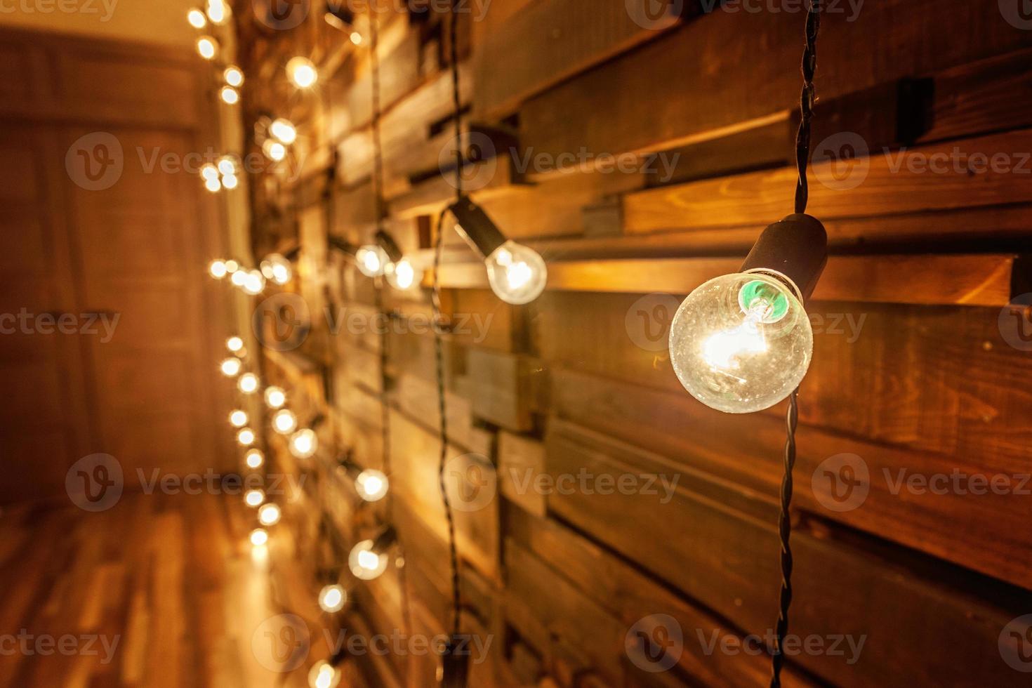 Modern dark classical style interior design apartment with retro lamps hanging light bulbs background. Wooden planks with lamps. Decorated interior room with gold lights. Copy space mockup poster. photo