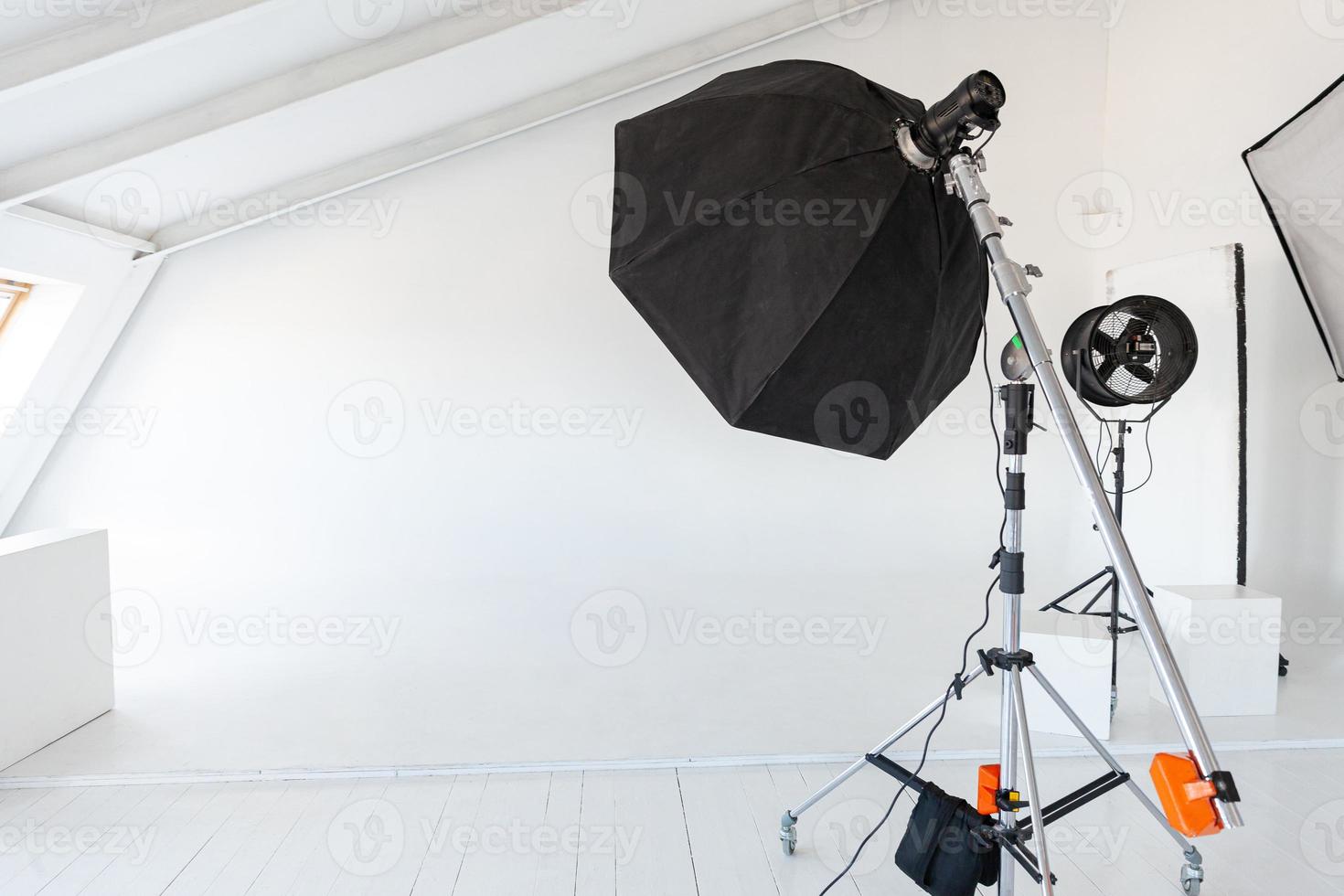 estudio fotográfico vacío con equipo de iluminación. interior del lugar de trabajo del fotógrafo con equipo de herramientas profesionales. escenas de fondo blanco con luz de flash listas para disparar en estudio. estudio de fotógrafo moderno foto