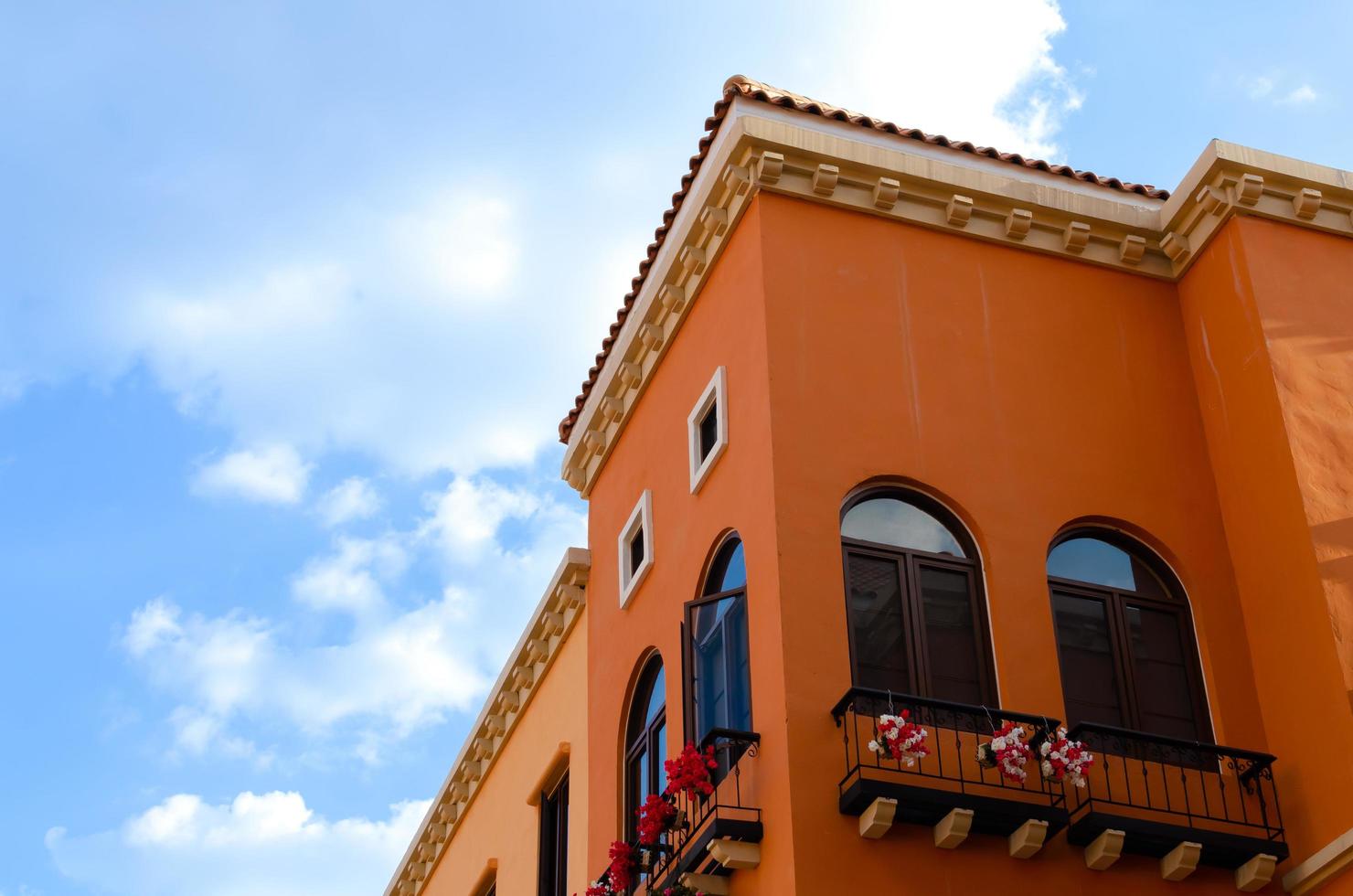 Colorful orange building with black and white window frames. Look up to the blue sky. photo