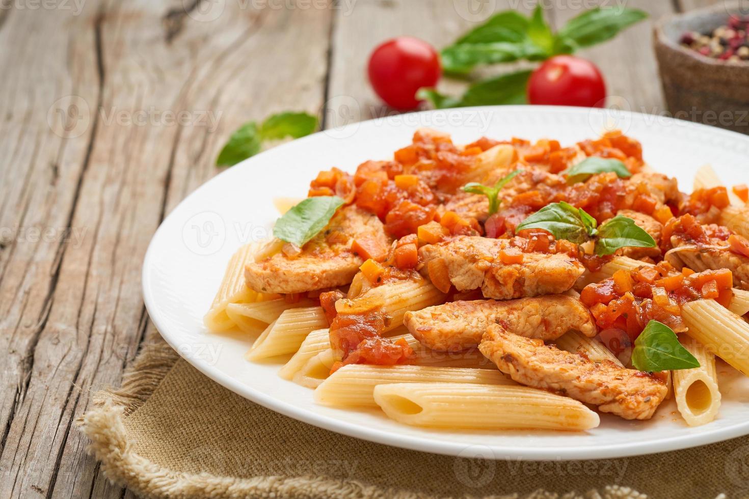 Penne pasta, chicken or turkey fillet, tomato sauce with basil leaves photo