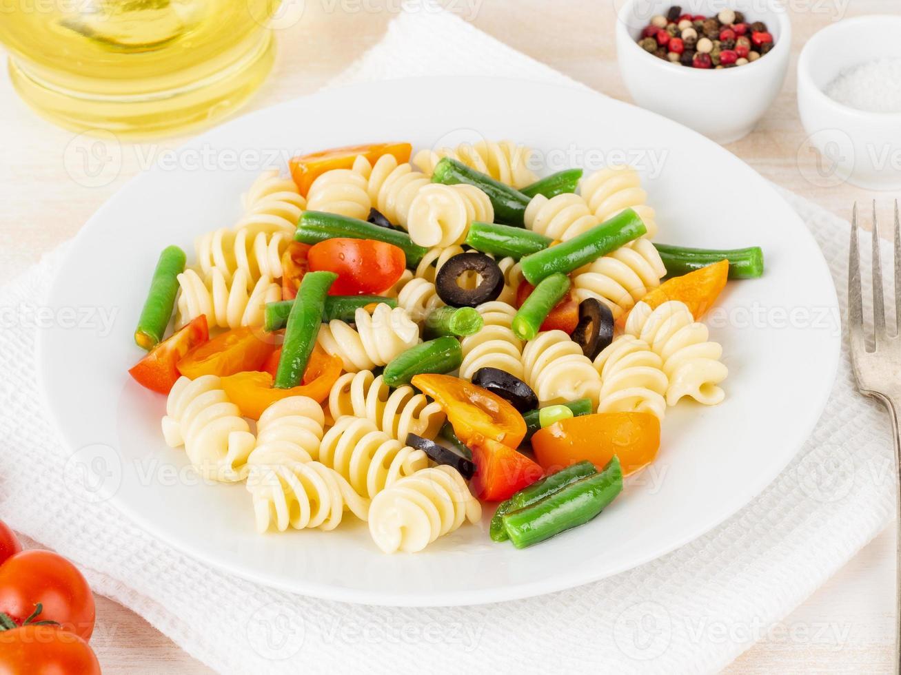 Italian salad with fusilli paste tomatoes, olives, green beans, side view, close up photo