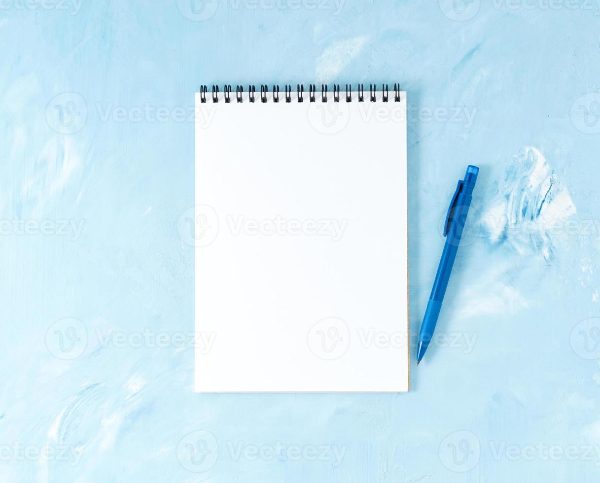 Top view of modern bright blue office desktop with pen or pencil, notepad. Mock up, empty space photo