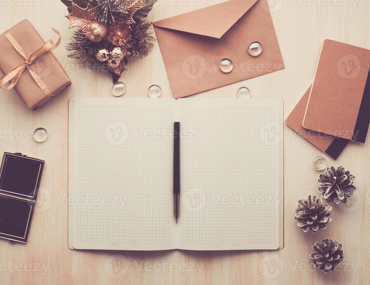 white open notepad, envelope and Christmas decoration lying on beige wooden background photo