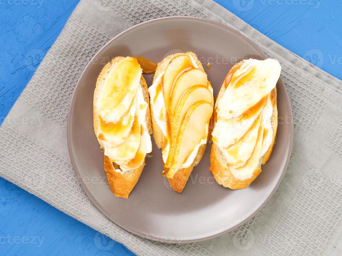 Plate with three delicious French toast with bananas, pears, cream cheese, caramel syrup photo