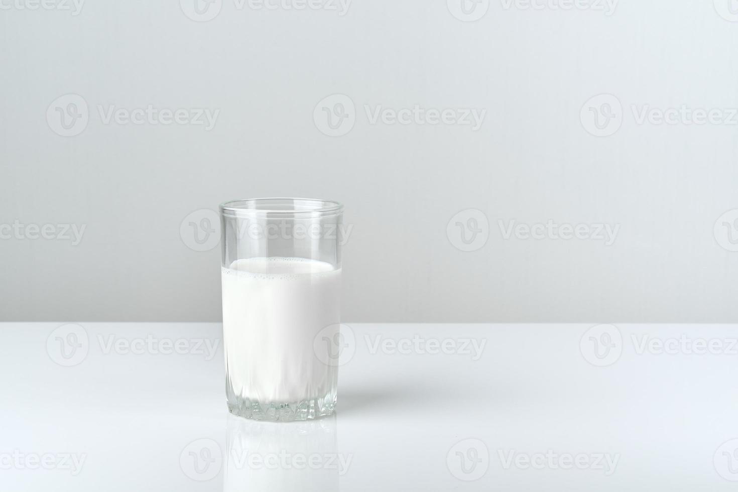 vaso de leche sobre mesa blanca sobre fondo gris, vista lateral foto
