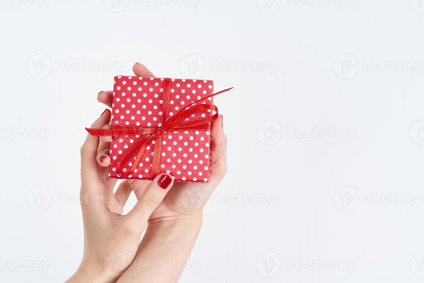 woman hands holding red gift with ribbon, manicured hands with nail polish photo