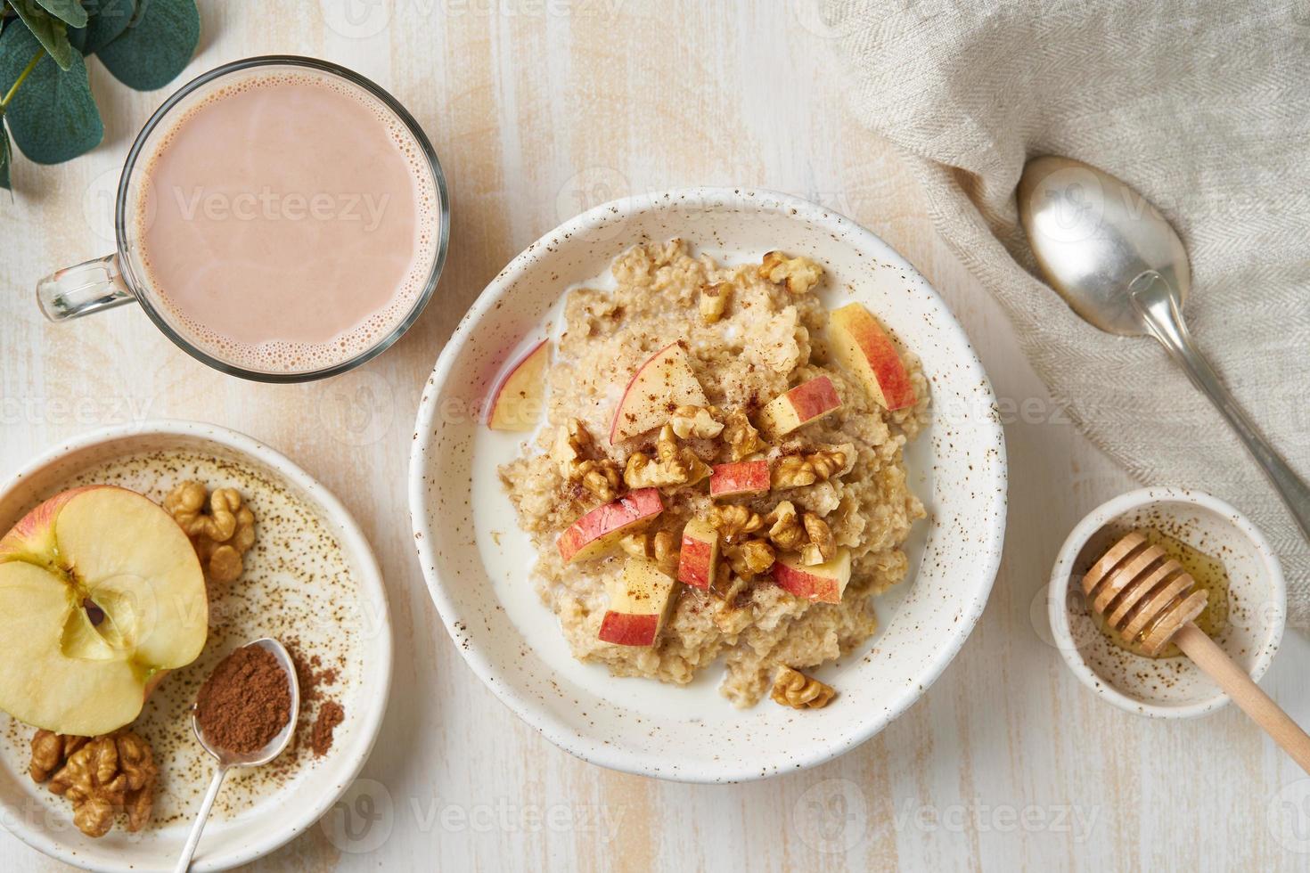 Oatmeal with apple, nuts, cinnamon, honey and cup of cocoa photo