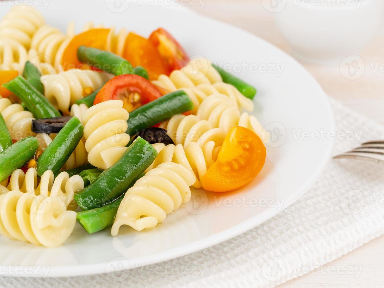 Italian salad with fusilli paste tomatoes, olives, green beans, part of, side view, close up photo