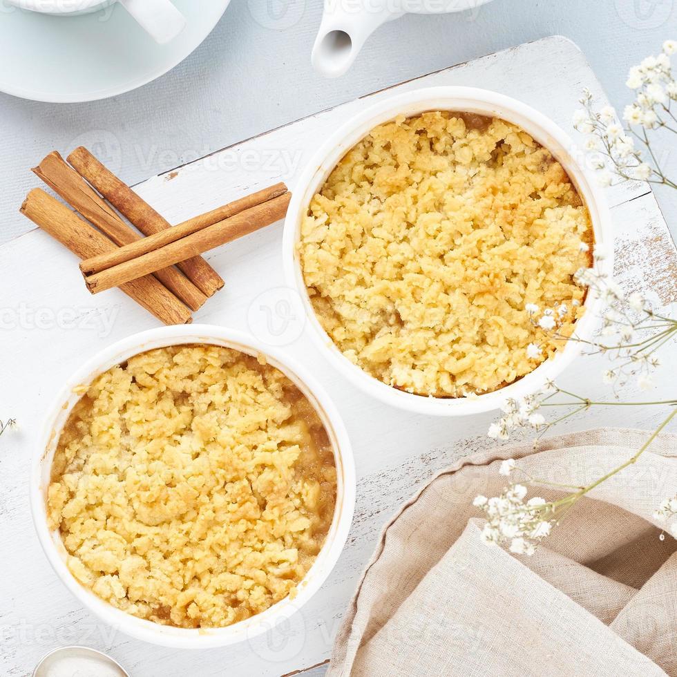 Apple crumble with streusel on light gray table. Morning breakfast with a flowers. photo