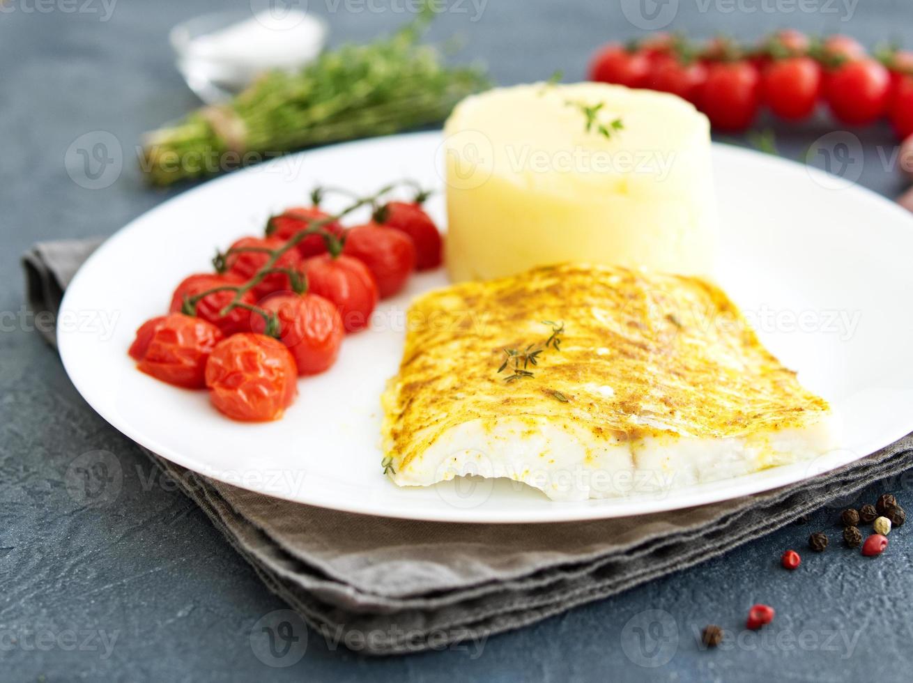 bacalao de pescado al horno con puré de patatas, tomates, comida dietética saludable. fondo gris oscuro foto