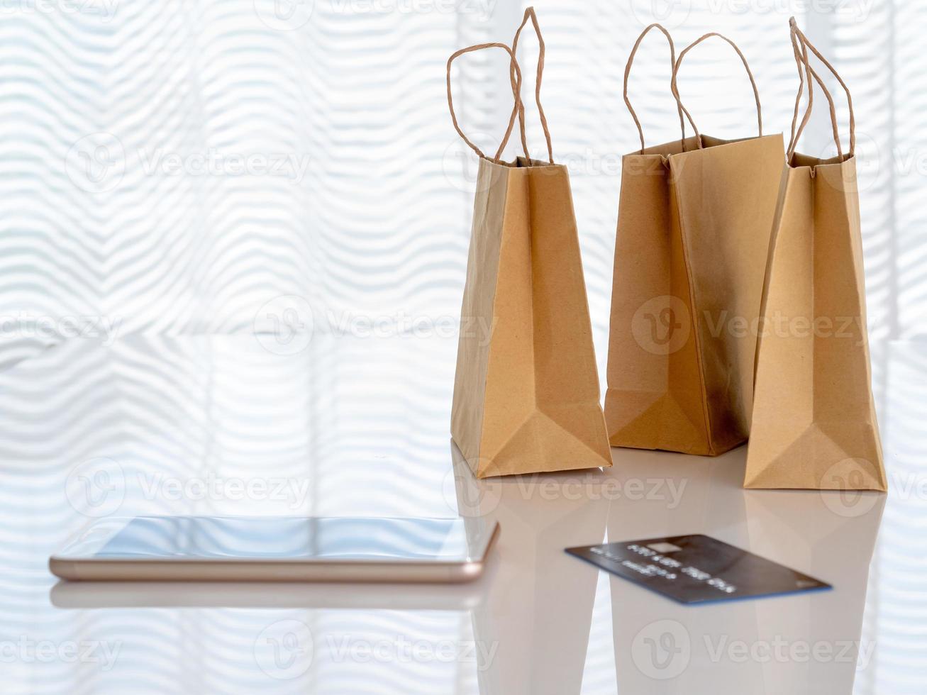 paquetes artesanales con compras, teléfono inteligente, tarjeta de crédito en la mesa frente a la ventana, concepto de compras en línea, espacio de copia foto