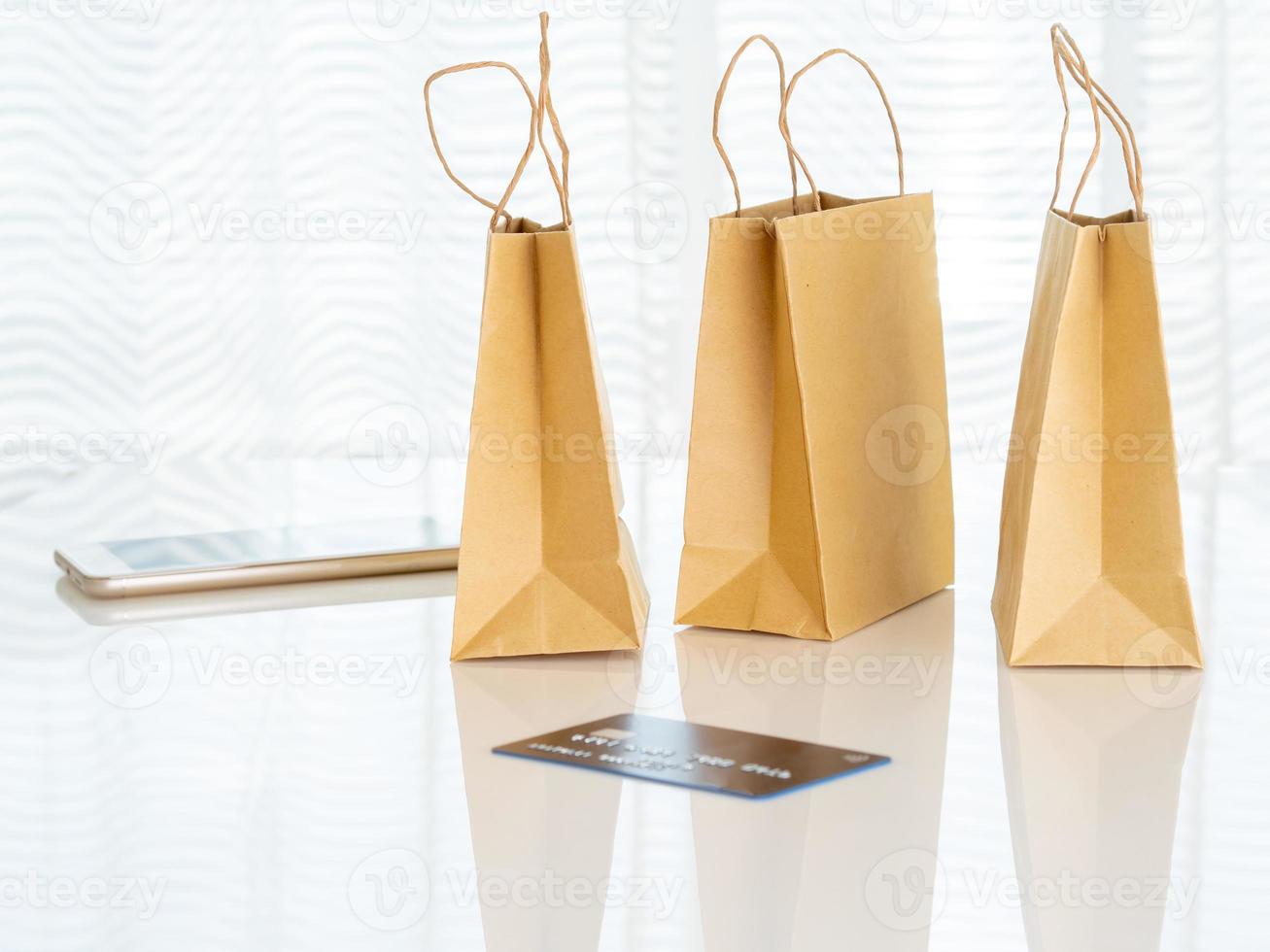 paquetes artesanales con compras, teléfono inteligente, tarjeta de crédito en la mesa frente a la ventana, concepto de compras en línea, espacio de copia foto