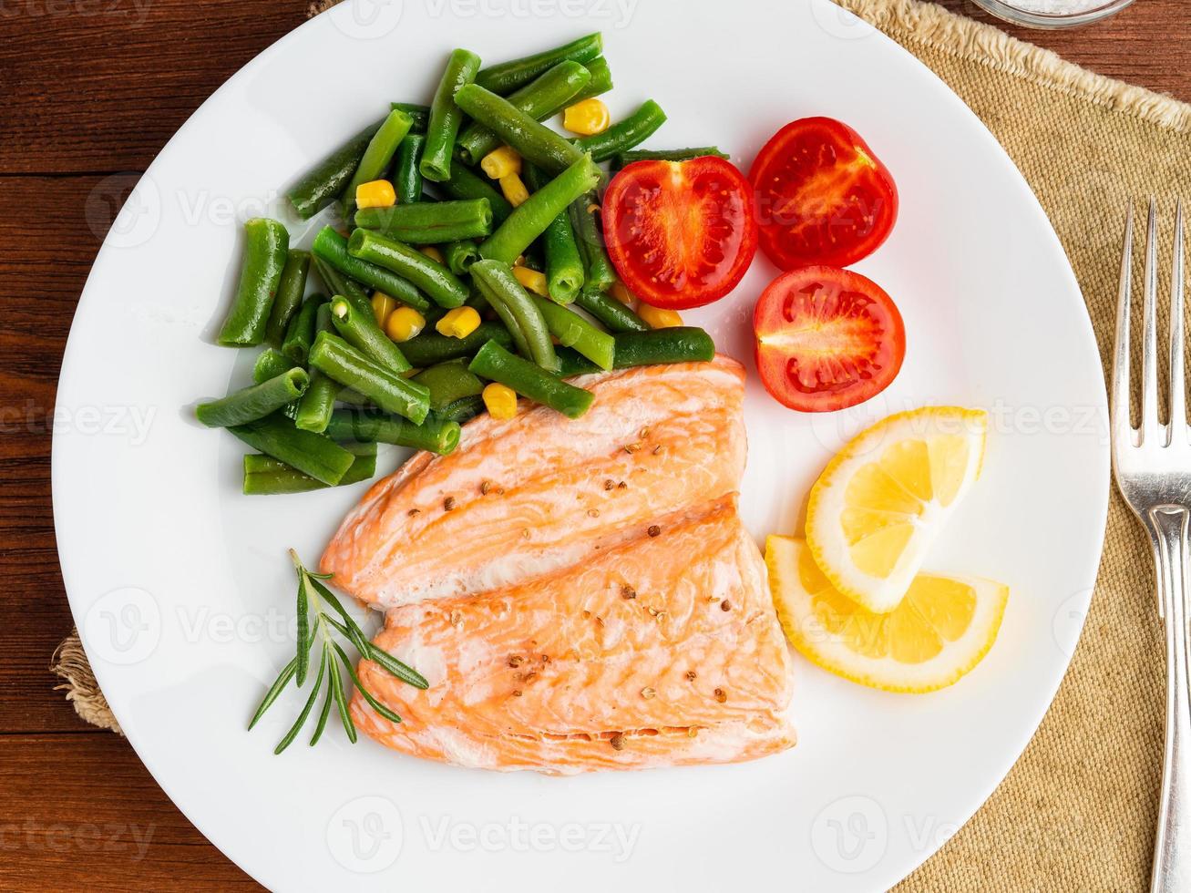 pescado salmón al vapor con verduras. comida de dieta saludable, telón de fondo de madera oscura foto