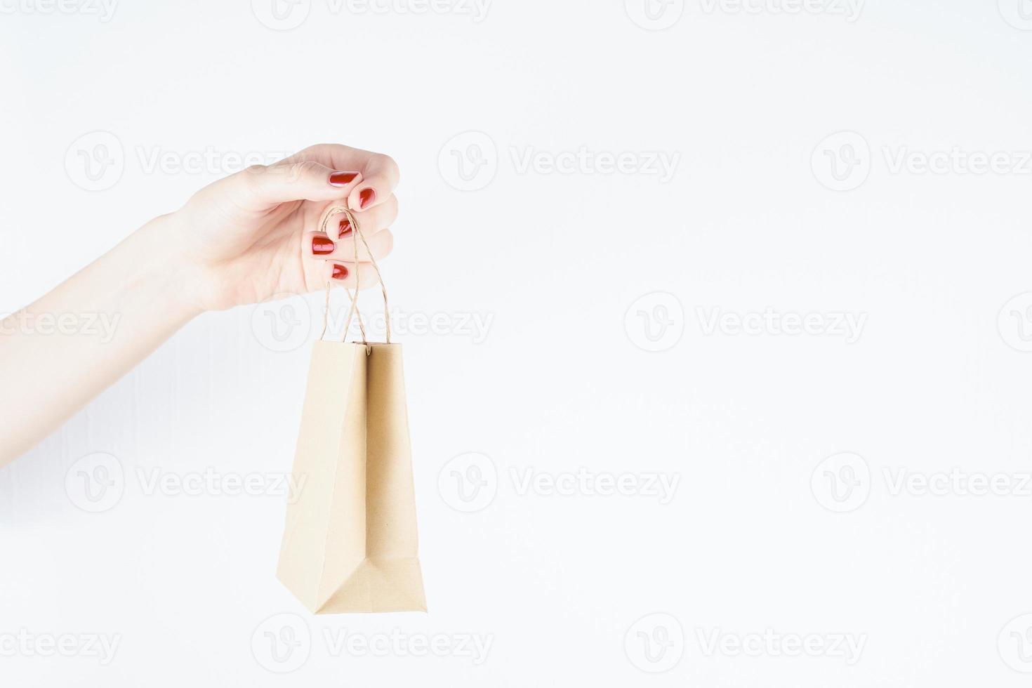 woman holding paper bag on white background, person with red nail polish, mockup design, copy space photo