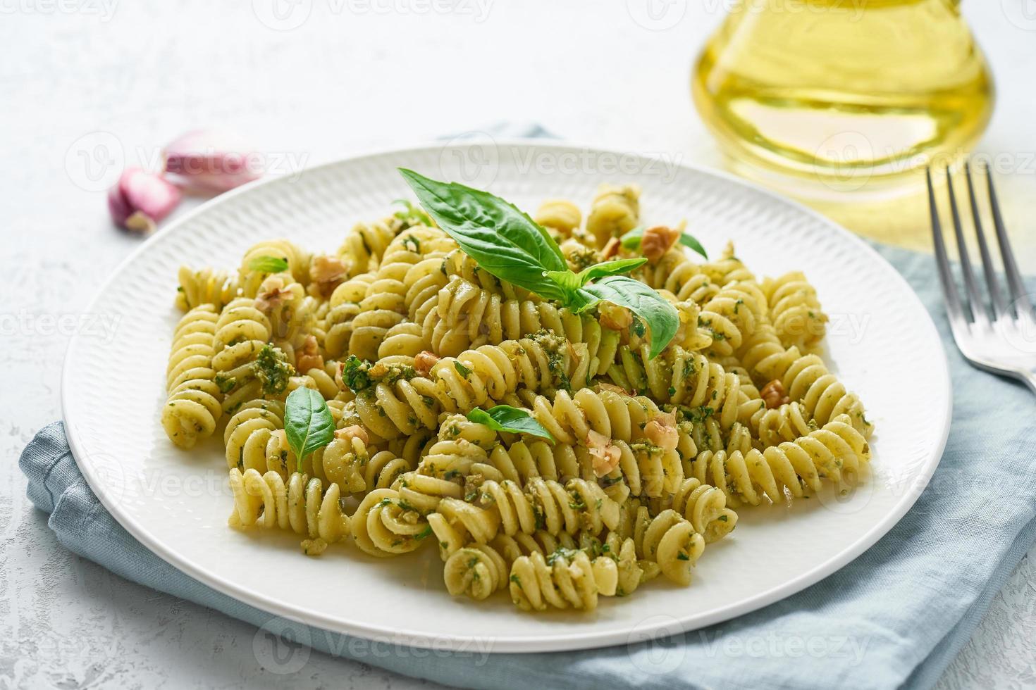 fusili pasta with basil pesto and herbs, italian cuisine, gray stone background, closeup photo