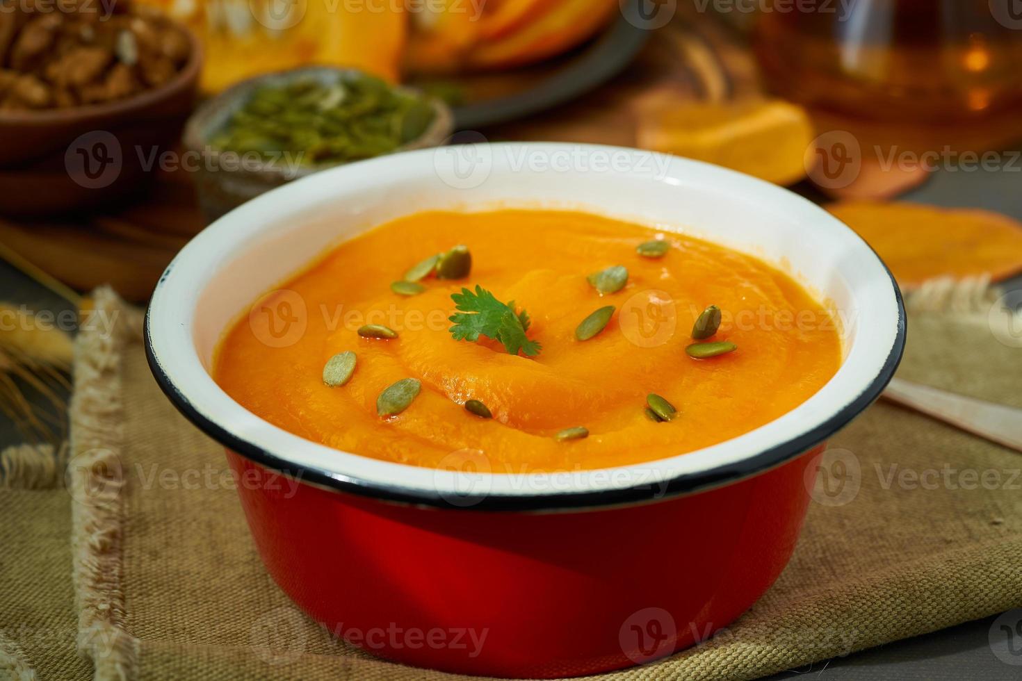 Closeup of pumpkin soup, autumn dish, healthy food, seeds and walnuts on background photo