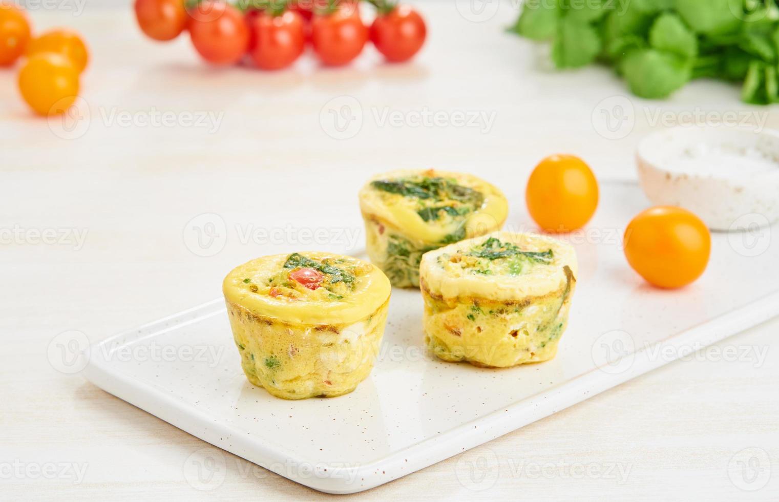 Egg muffins, paleo, keto diet. Omelet with spinach, vegetables, tomatoes baked in small molds photo