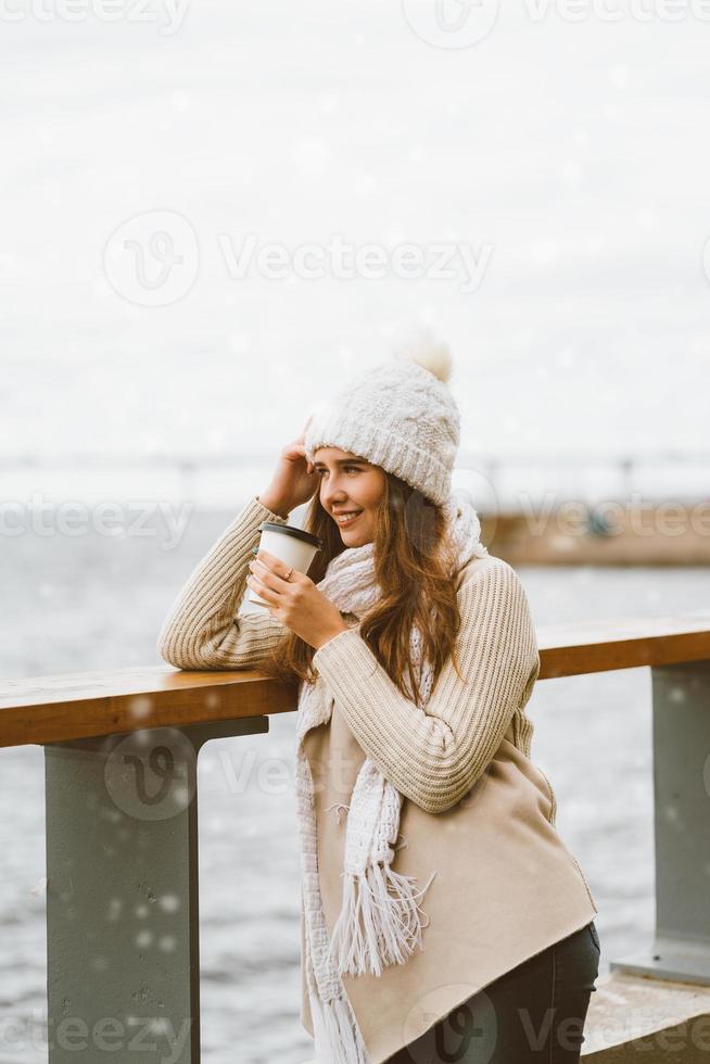 Beautiful young girl drinking coffee, tea from plastic mug. Winter, Christmas eve, new year's eve. Woman with long hair prepares to travel, Scandinavian style photo