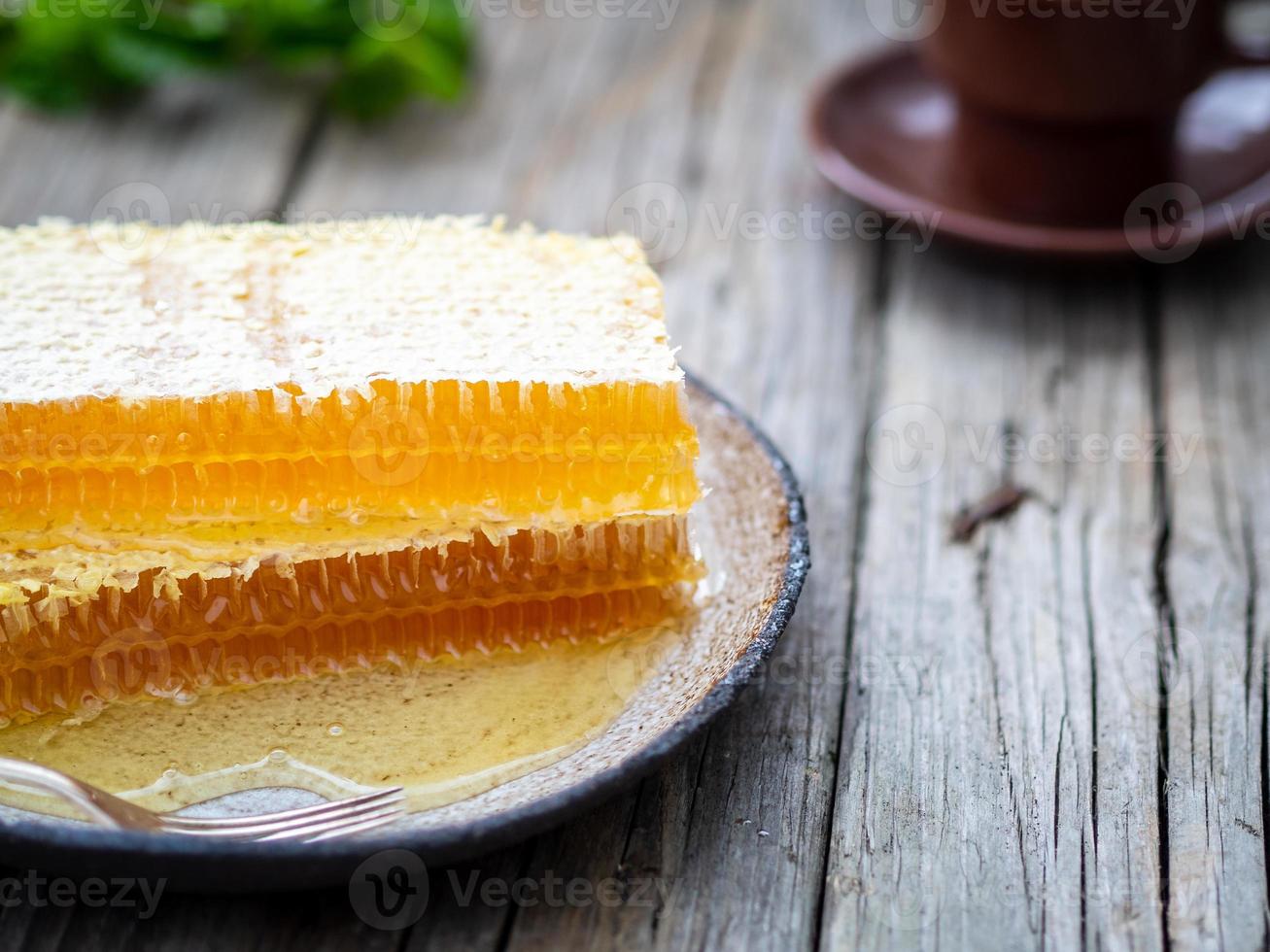 honey in honeycomb, close-up, on white ceramic plate, on wooden rustic table, photo