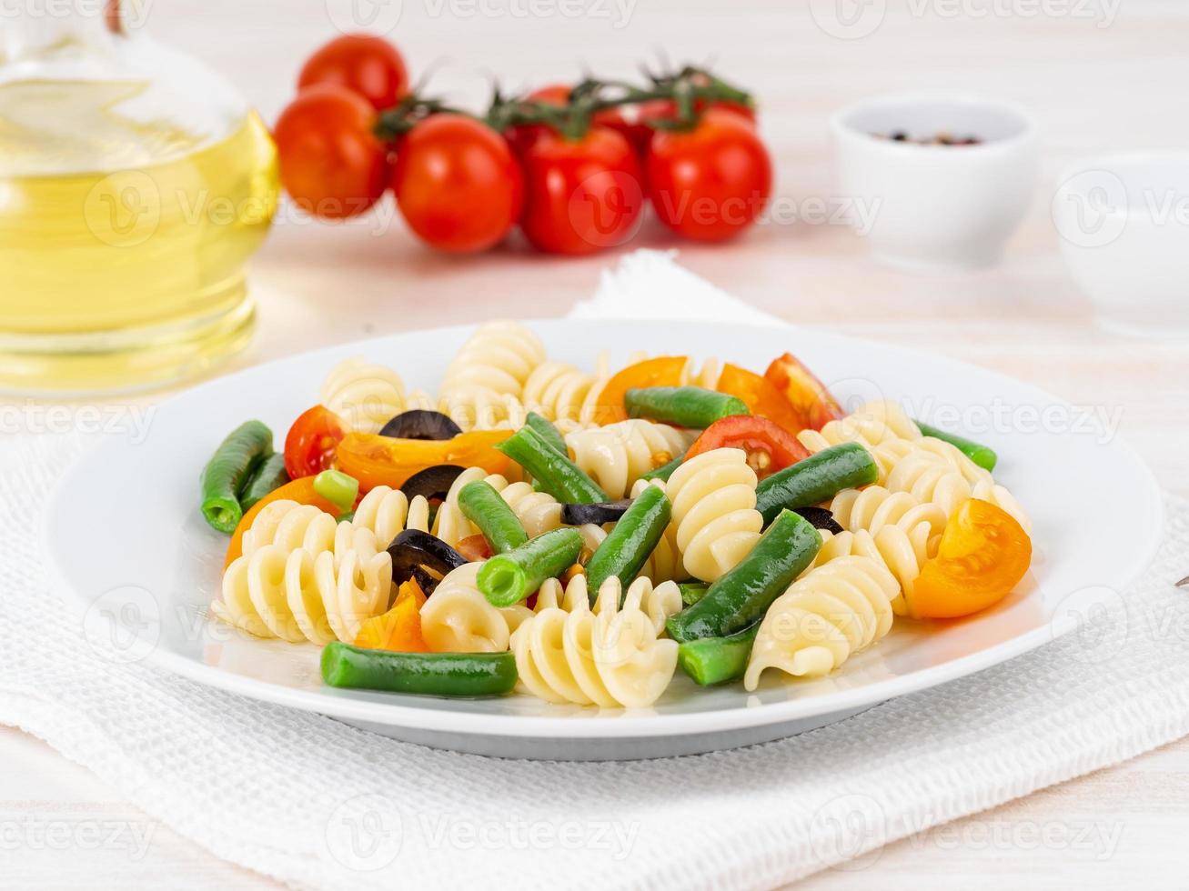 Italian salad with fusilli paste tomatoes, olives, green beans, side view, close up photo