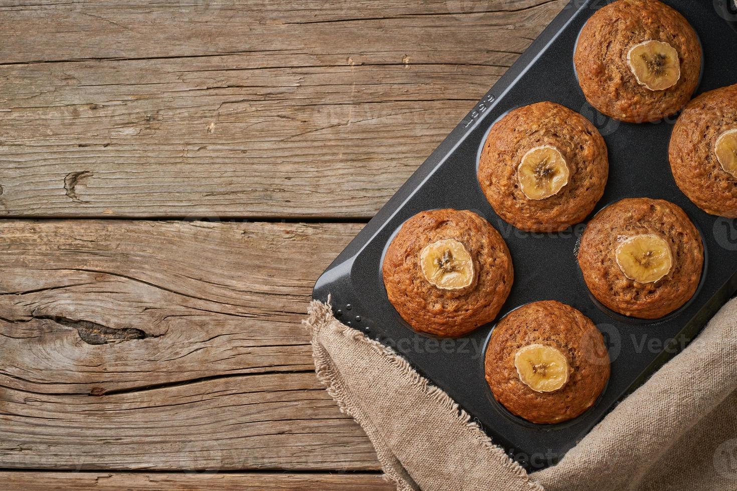 Banana muffin in tray, top view, copy space. Cupcakes on old linen napkin, photo
