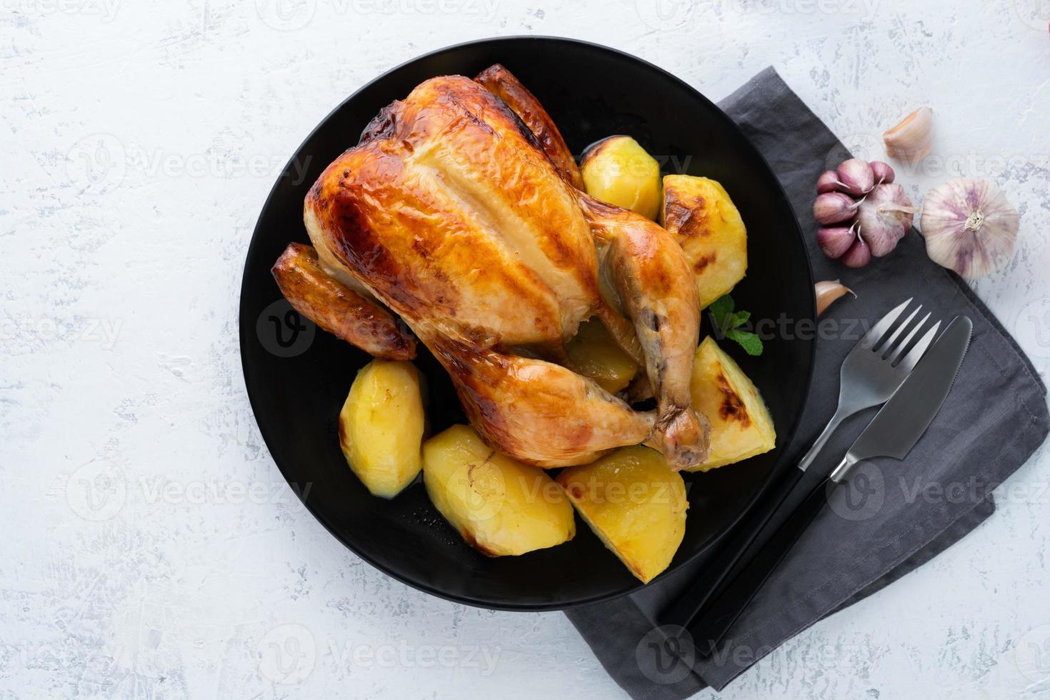 pollo entero a la parrilla en plato sobre mesa blanca, carne al horno con patatas. vista superior, espacio de copia foto