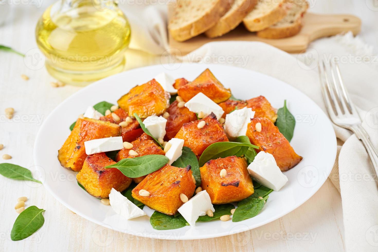 Salad with roasted pumpkin, feta cheese, spinach, nuts with honey and seasonings, side view photo