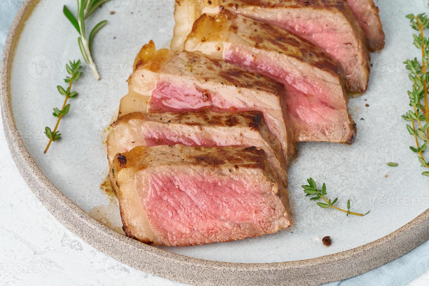 Keto ketogenic diet beef steak, striploin on gray plate on white background. Paleo food photo